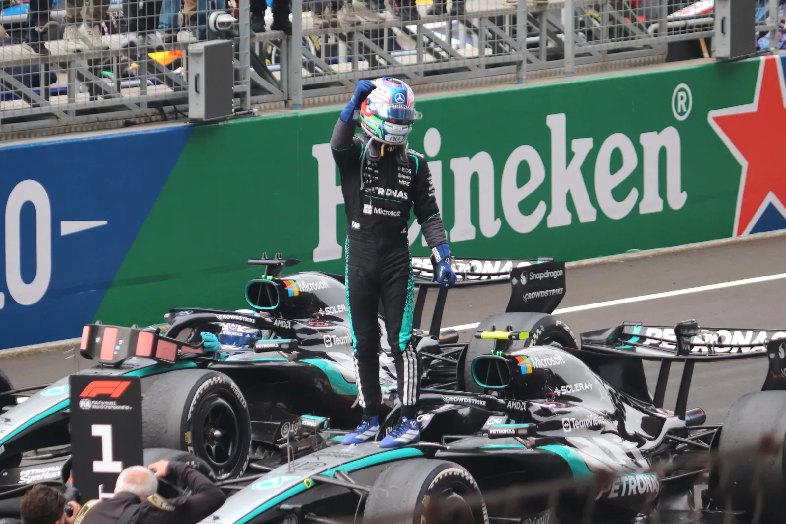 Kimi Antonelli stands on his Mercedes beside the number one board after winning in China