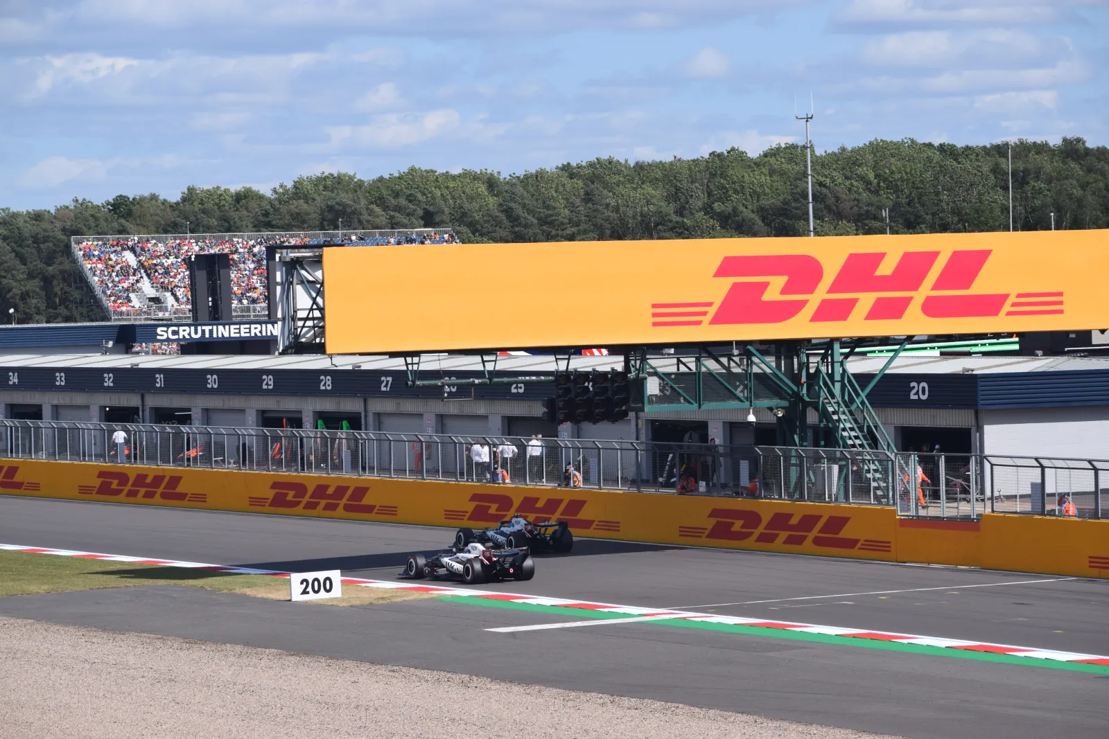Os dois carros da Cadillac na reta dos boxes de Silverstone, com as garagens da equipe ao fundo