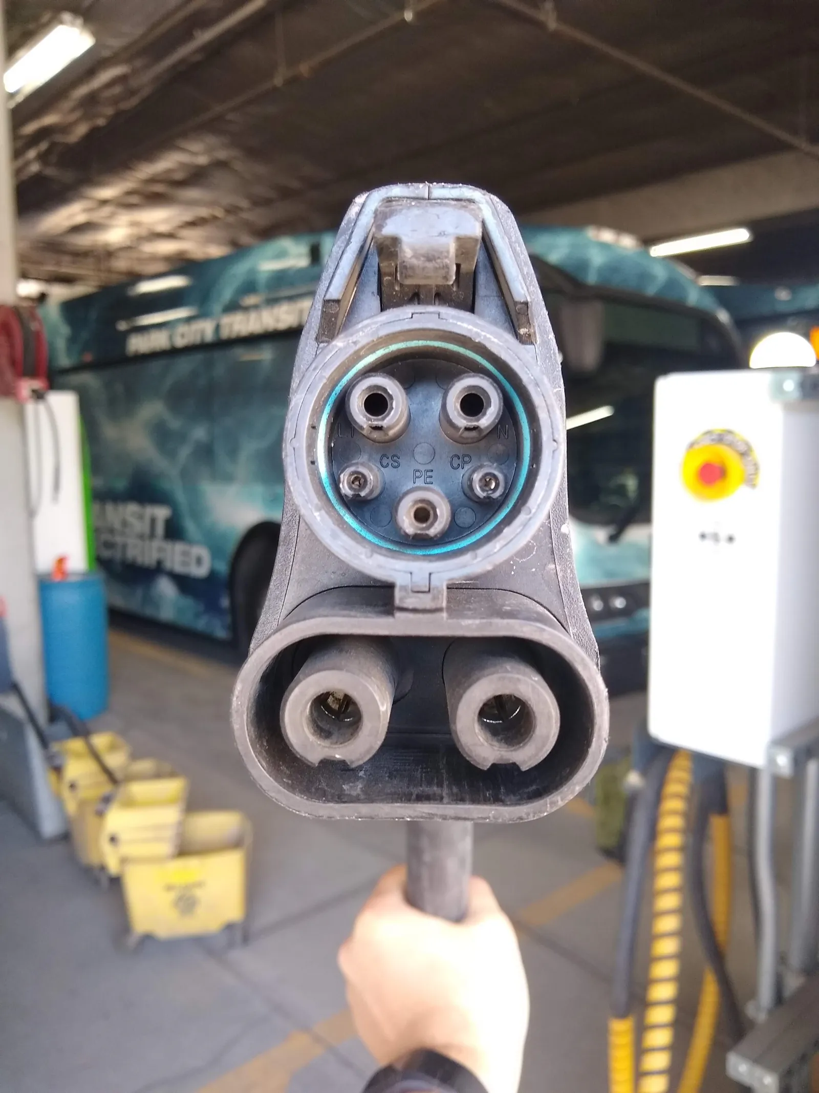 CCS1 fast charging connector held up at an electric bus depot