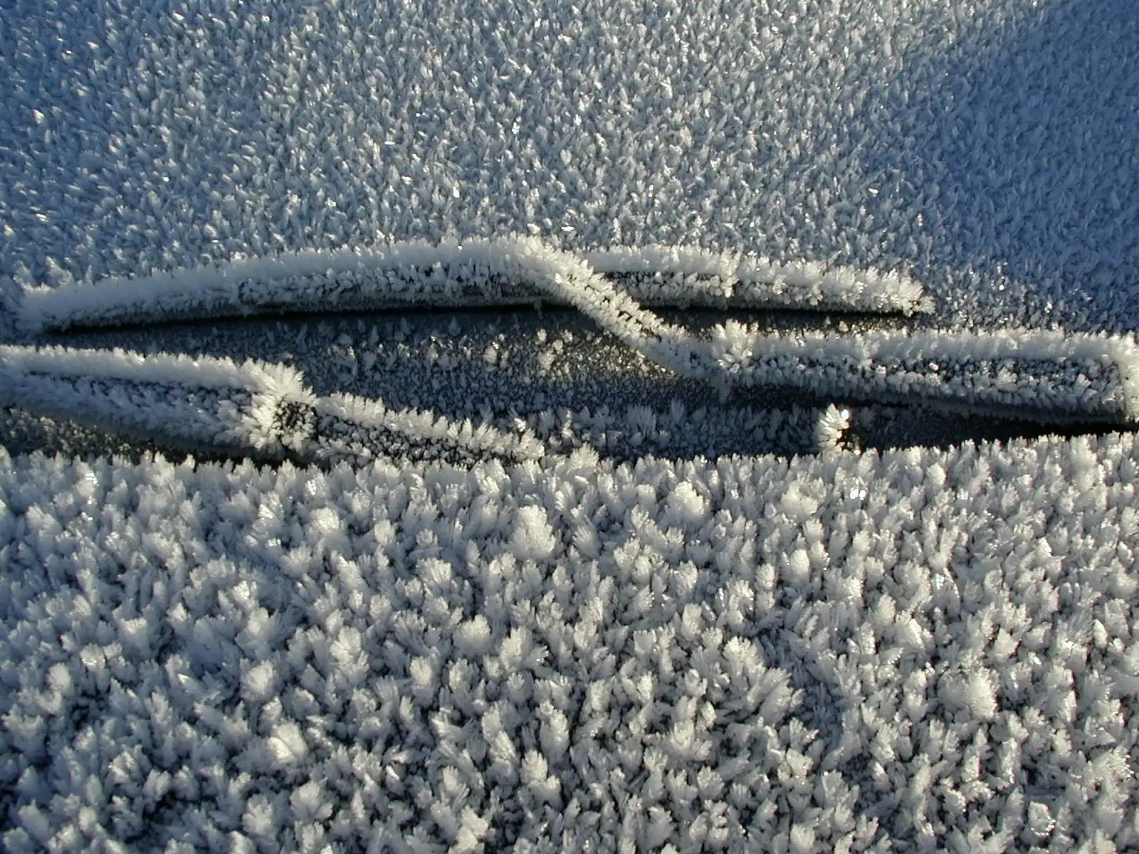 Thick hoar frost covering a windscreen and wiper blades on a freezing morning