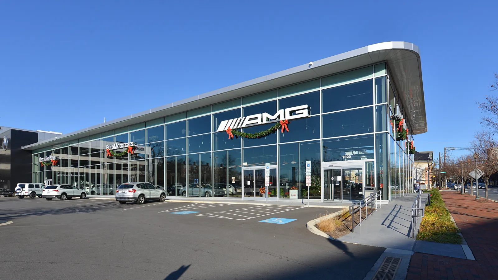 Glass-fronted Mercedes-Benz dealership showroom with new cars parked outside