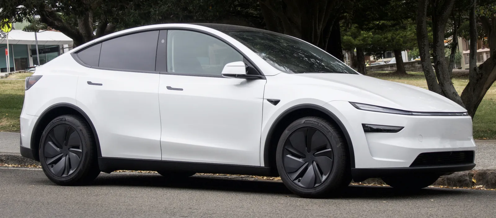 White Tesla Model Y parked kerbside showing the refreshed front light bar