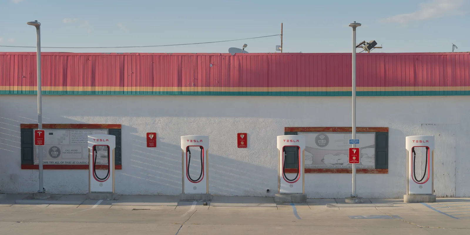 Four empty Tesla Supercharger stalls beside a roadside diner in Inyokern California
