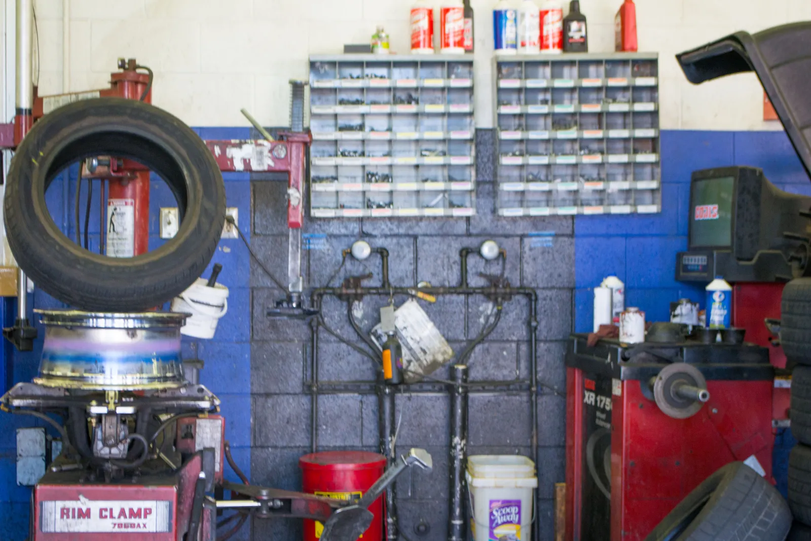 Tyre being fitted on a rim clamp machine inside a workshop with spare tyres stacked nearby