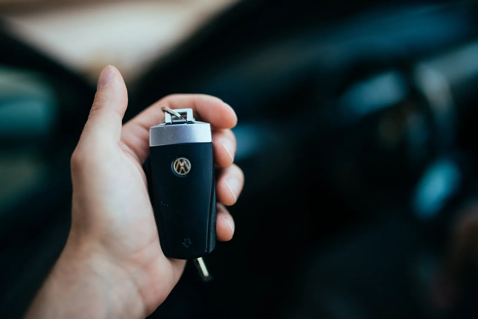 Buyer holding a car key and fob standing in front of a parked car